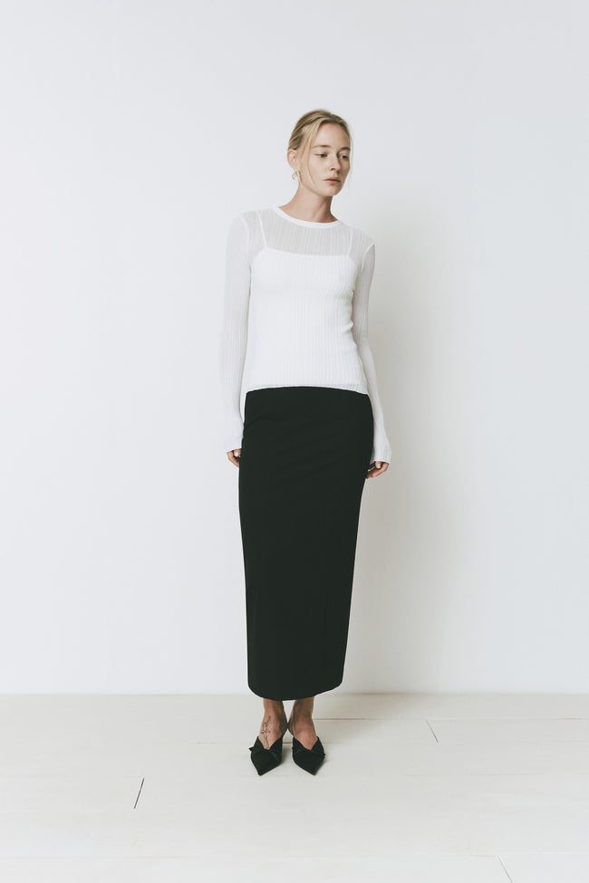 Ruesophie Iris white sheer long-sleeve knit sweater styled with a black maxi skirt for a minimalist look.