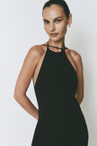 Black Opera Dress with halter neck, midi length, and open back. Featuring a model.