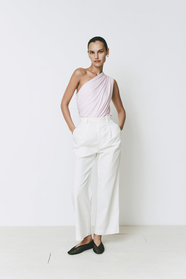Perle bodysuit in pink with one-shoulder design and ruched detail, paired with white trousers