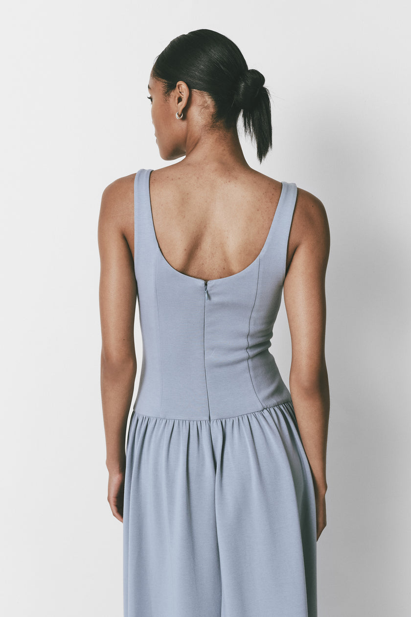 Light blue midi dress with drop waist, square neckline, smooth fabric, and back zipper detail