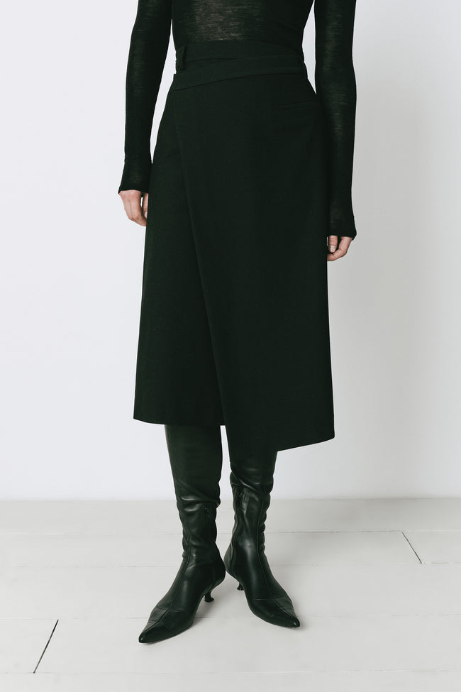 Black wrap skirt with surplice front, black top, and leather boots. A versatile piece for day or evening wear.