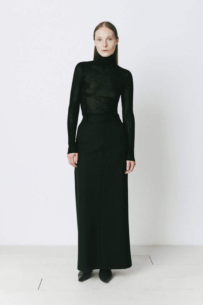 Black maxi skirt paired with a turtleneck top. Sophisticated style, ideal for fall/winter.