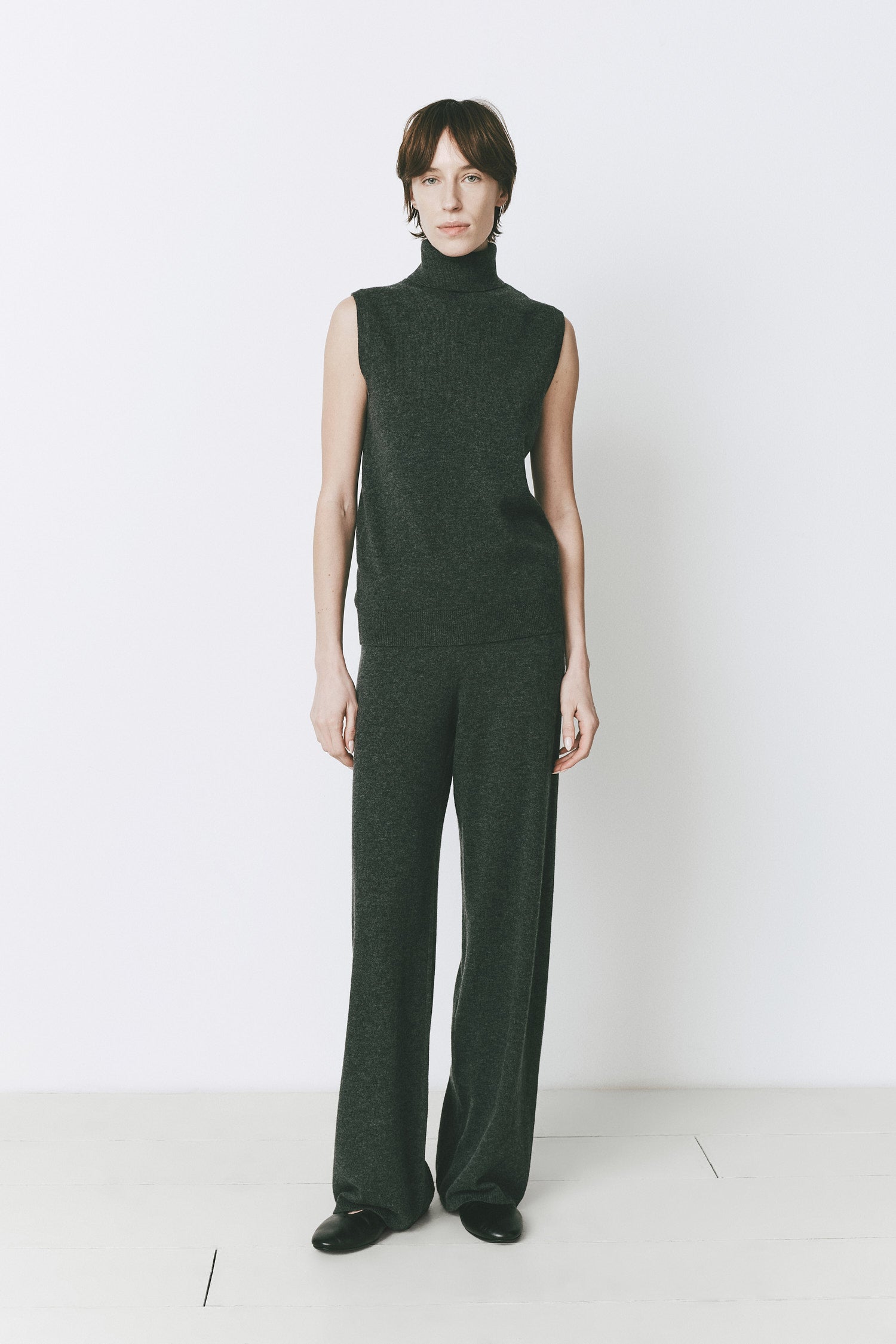 Denis S/L Topaz Turtleneck Knit Top. Woman wearing a wool-cashmere turtleneck sweater and pants in forest green.