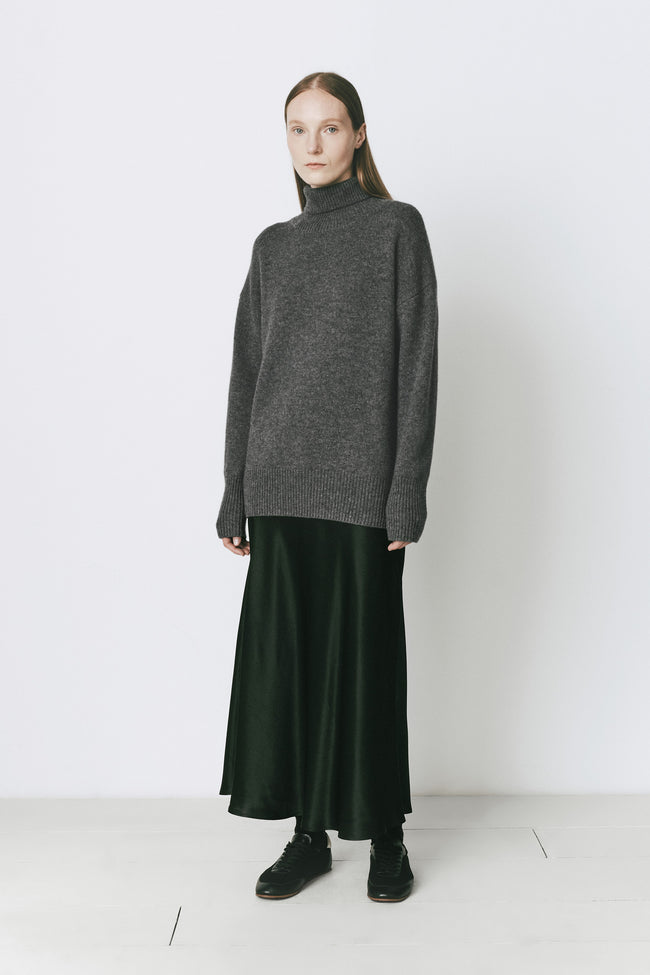 Garches Turtleneck Sweater in Cinder, styled with a dark green skirt, ideal for cold weather.