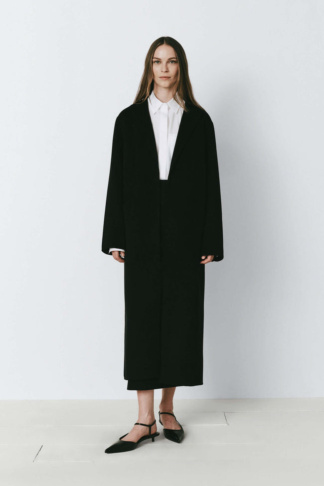 Mathé Belted Double-Faced Coat in black, oversized wool and cashmere coat with a long design. Woman wearing the coat.