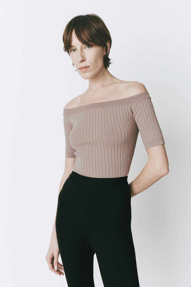 Wheat-hued off-shoulder top, viscose-nylon blend, paired with black pants. Elegant minimalist design