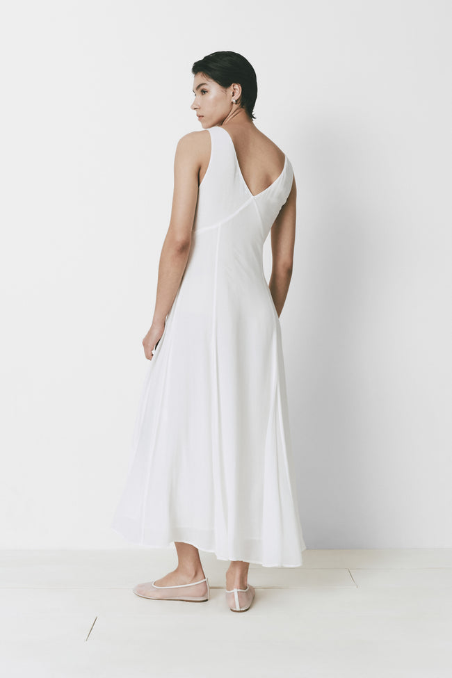 Narbonne Dress in white. A flowing, lightweight, semi-sheer dress with a V neckline.