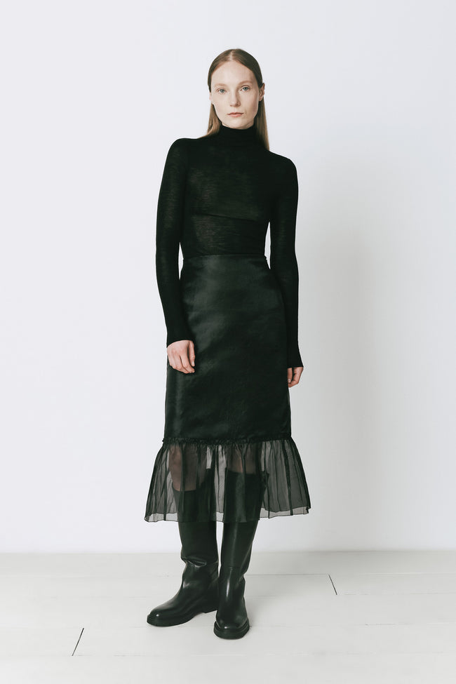 Panthéon Turtleneck Top, black wool turtleneck, black skirt with tulle, and black leather boots. Sophisticated look.