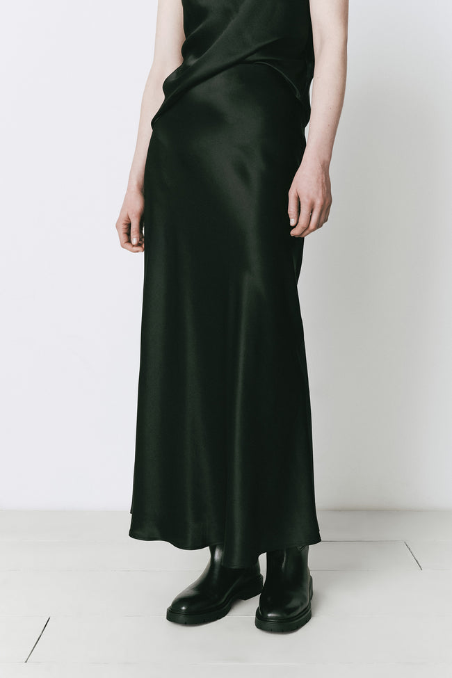Black silk maxi skirt with elastic waist, paired with black boots. Fall elegance, fluid drape.