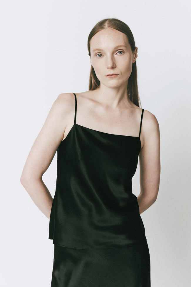 Black silk top with square neckline and spaghetti straps on a model.