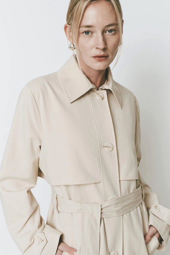 Cassis Trench Coat in beige. Classic design with wide collar and adjustable belt, cut with a relaxed fit.