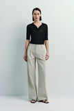 Model wearing Vélo Crinkled Cotton Wide Leg Pants, beige color, paired with a black shirt, showcasing the relaxed fit