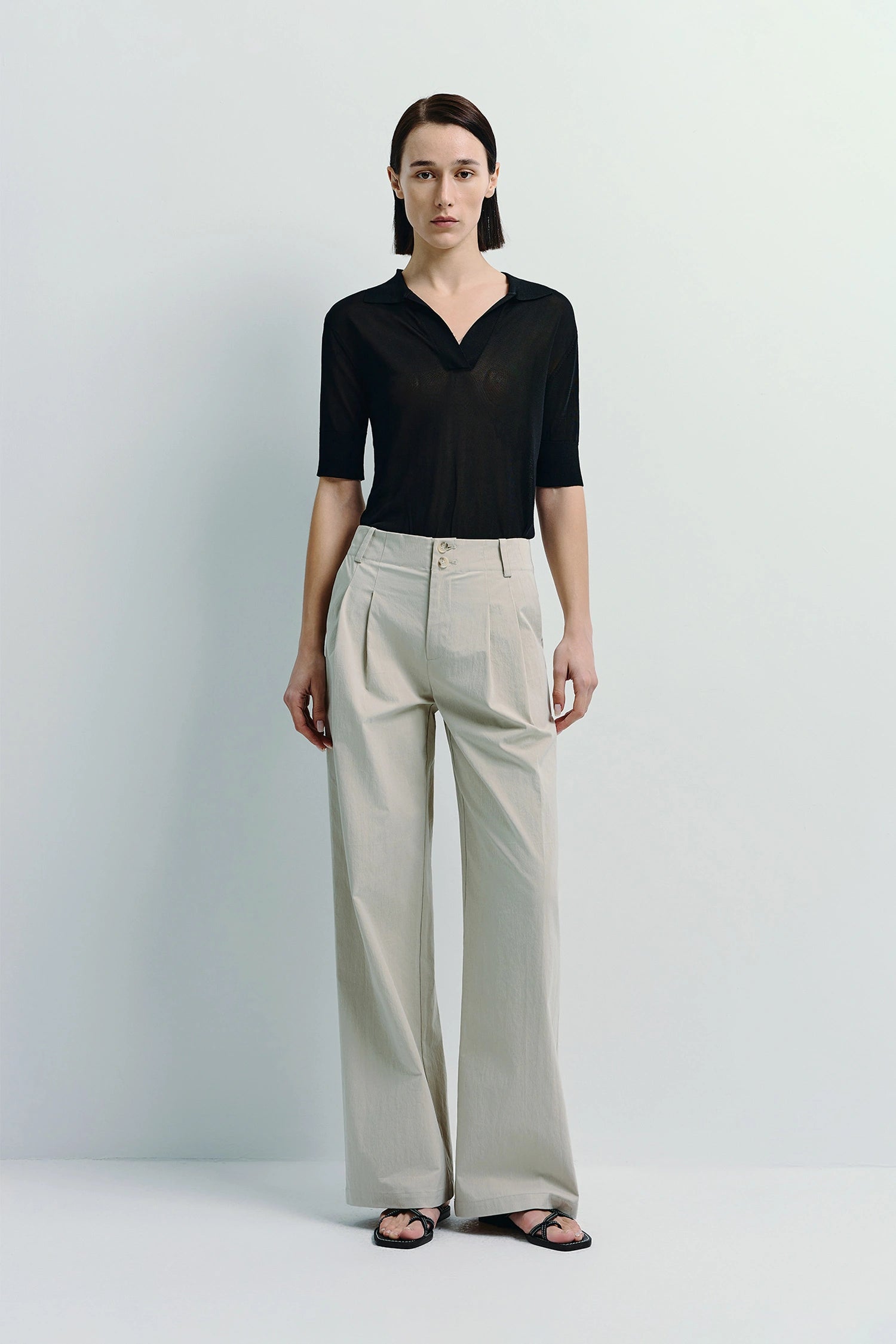 Model wearing Vélo Crinkled Cotton Wide Leg Pants, beige color, paired with a black shirt, showcasing the relaxed fit