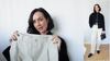A woman holds up a pair of Rue Sophie pleated trousers, with a full-length inset of the complete, stylish outfit