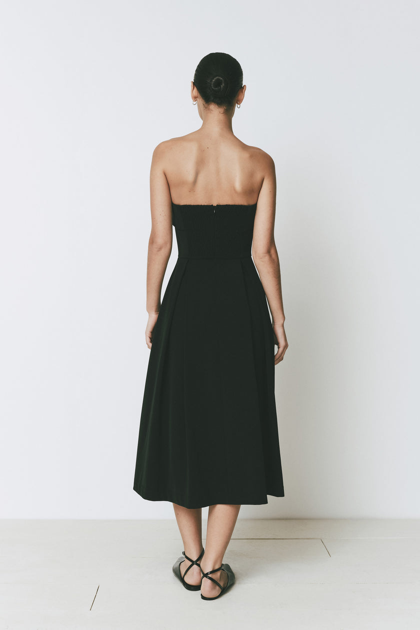 Belle Dress, black strapless A-line midi dress by Rue Sophie, back view on a model.