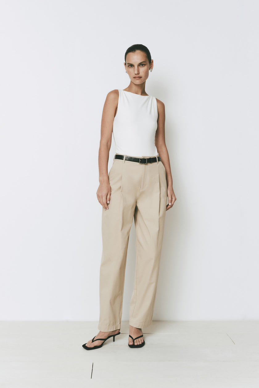 Sleeveless Plage Bodysuit in white, combined with beige trousers. Rue Sophie minimalist design.
