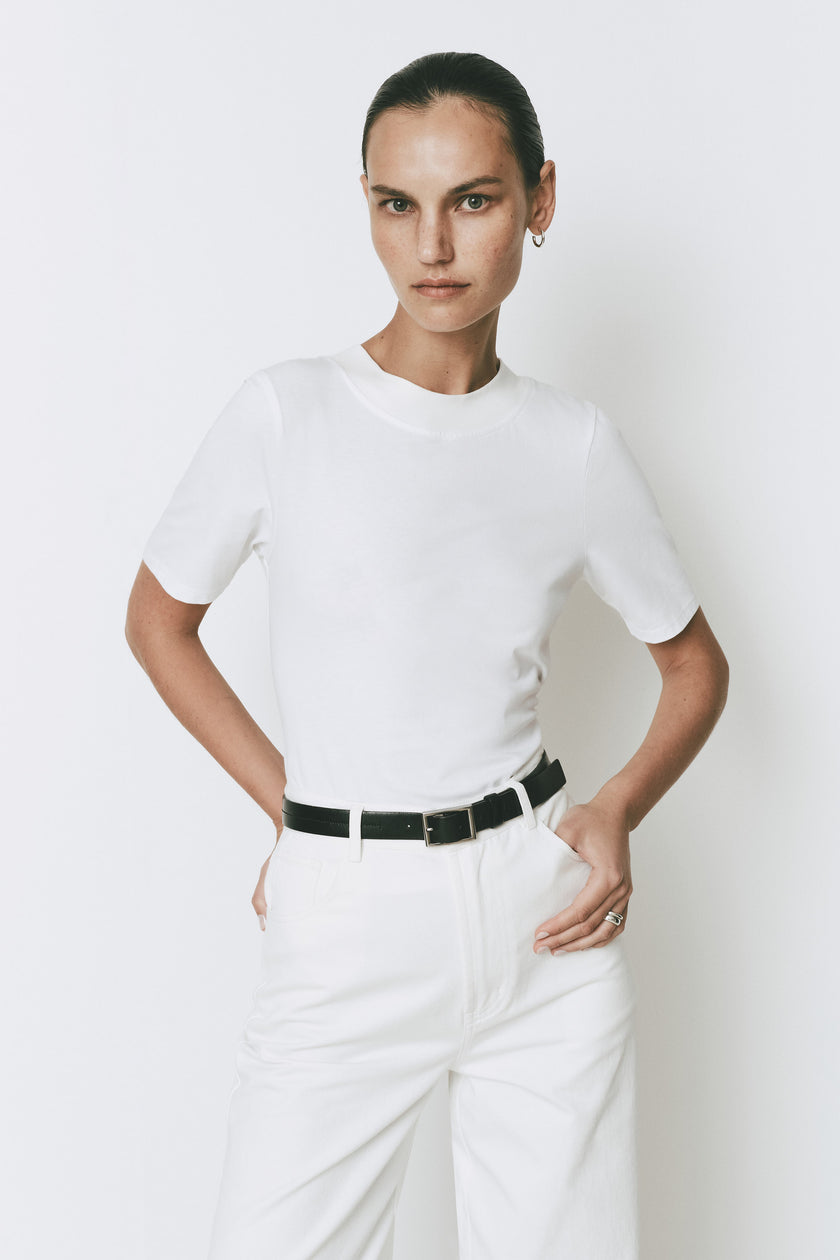 Ruesophie white Galerie Pant: mid-rise, wide-leg, flat front with jean-style pockets, worn with black belt.