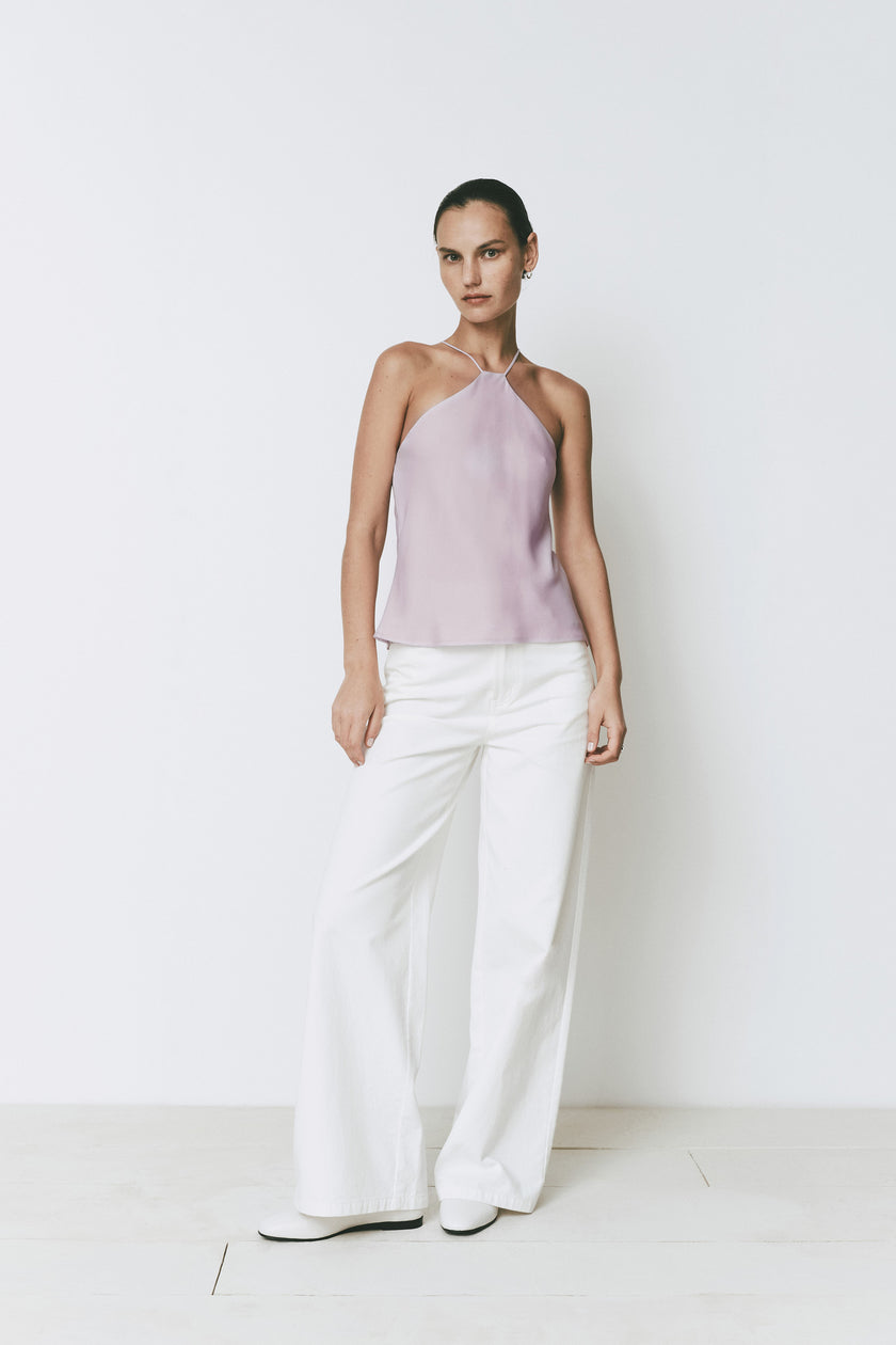 Rue Sophie Arc Top in light purple, paired with white trousers. Minimalist, halter top and back strap detail