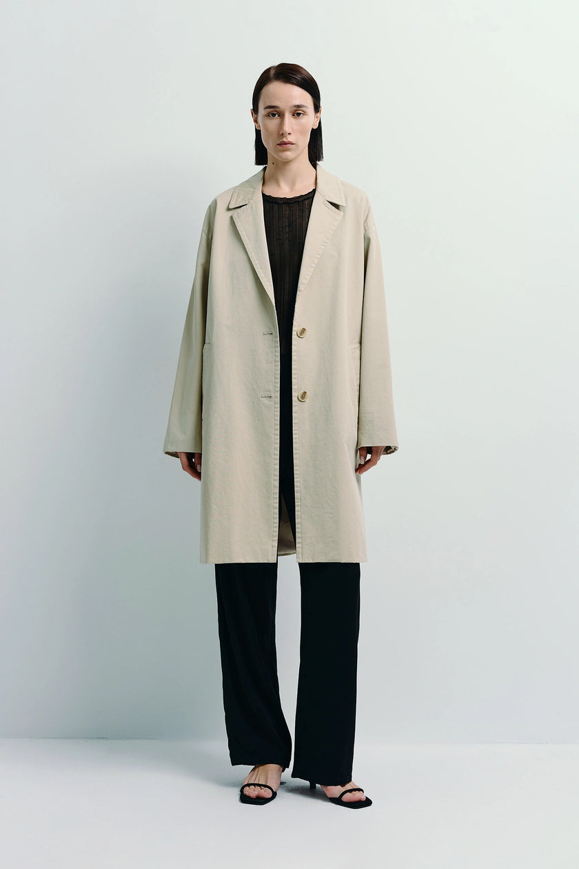 Dune Cotton Twill Coat in light beige, oversized fit. Model wearing black outfit