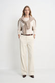 A model wearing Rue Sophie’s Talia Wide Leg Corduroy Pant in Winter White with an ivory long-sleeve top and a beige sweater draped over the shoulders, highlighting the relaxed wide-leg silhouette and full-length cut.