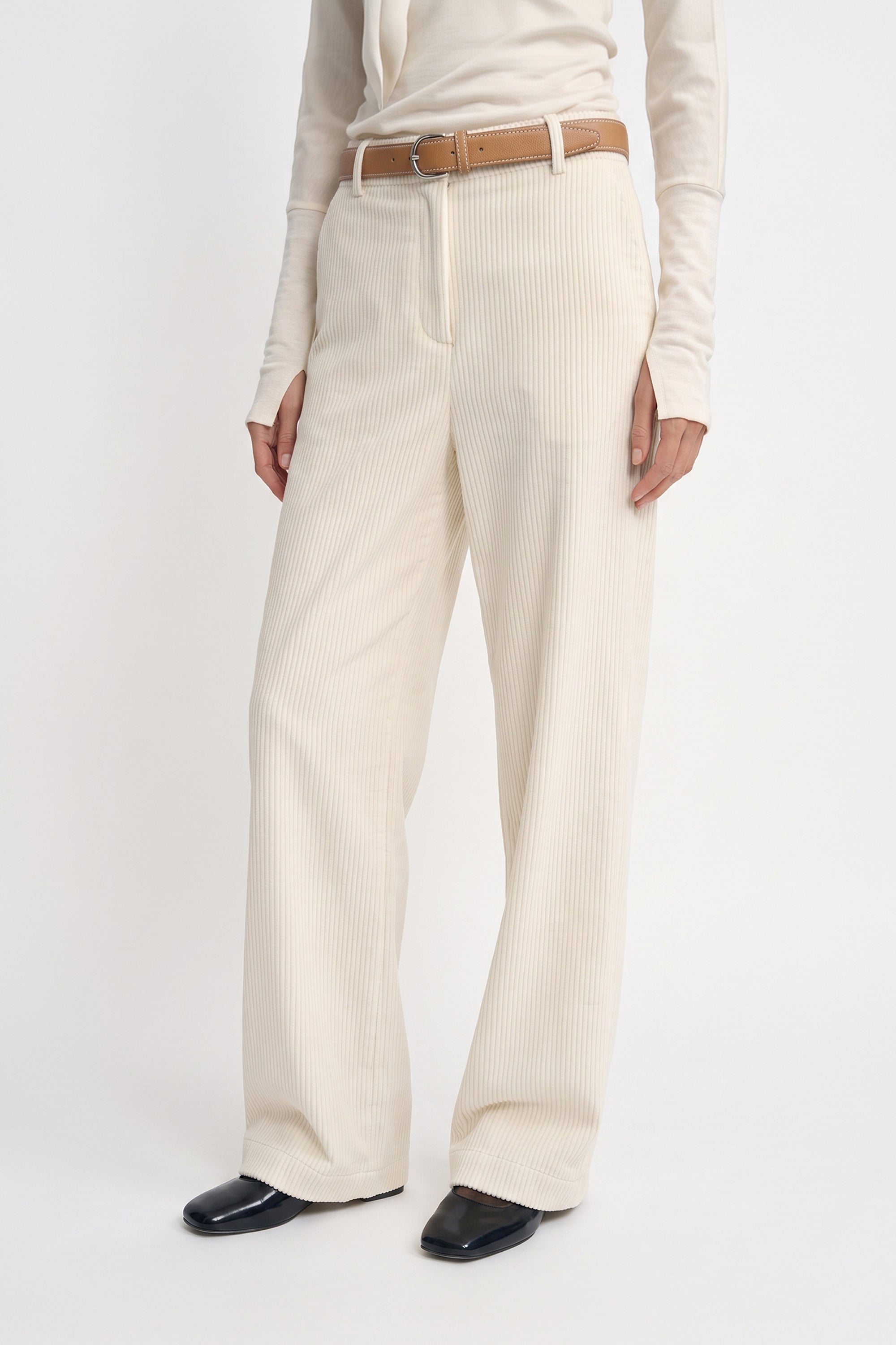 Close-up of Rue Sophie’s Talia Wide Leg Corduroy Pant in Winter White, showing the fine vertical corduroy texture, front fastening, belt loops, and wide-leg cut, styled with a tan leather belt and ivory top.