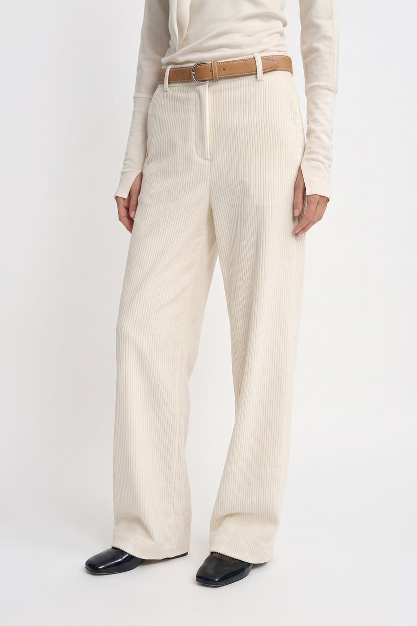 Close-up of Rue Sophie’s Talia Wide Leg Corduroy Pant in Winter White, showing the fine vertical corduroy texture, front fastening, belt loops, and wide-leg cut, styled with a tan leather belt and ivory top.