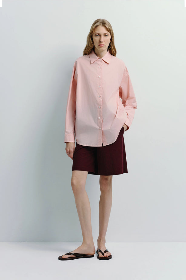 Woman in pink shirt and maroon linen Bermuda shorts. Versatile warm-weather shorts and top.