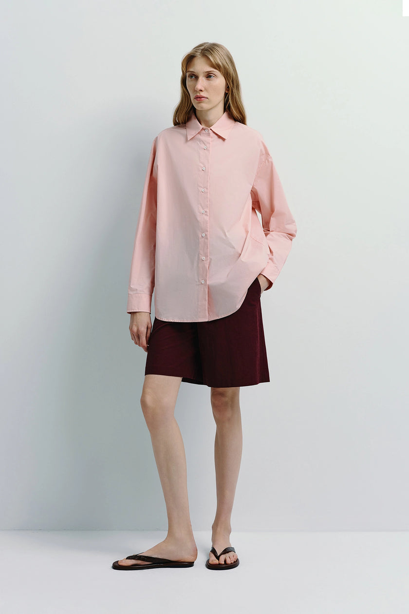 Woman in pink shirt and burgundy Lonan linen Bermuda shorts. Versatile warm-weather outfit.