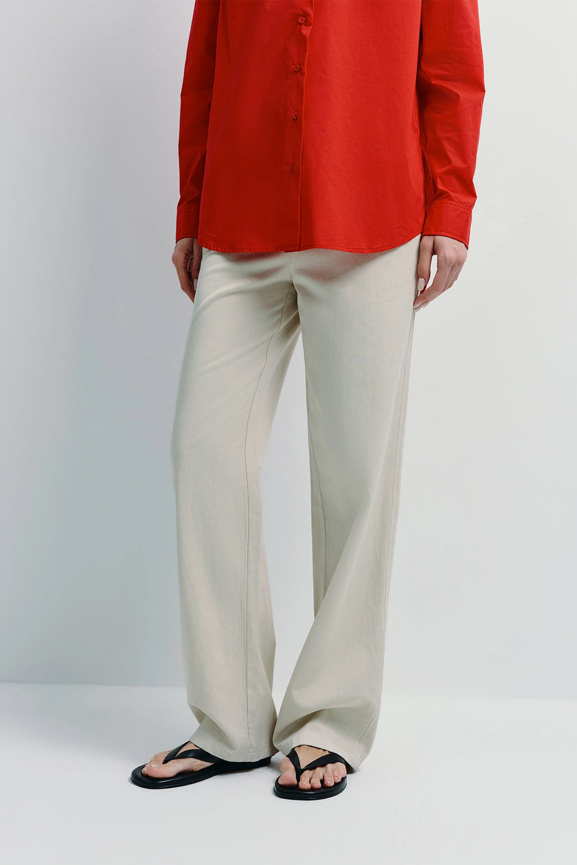 Metis Straight Leg Pant in cream with red shirt. Versatile cotton-lyocell blend, relaxed fit for any wardrobe.