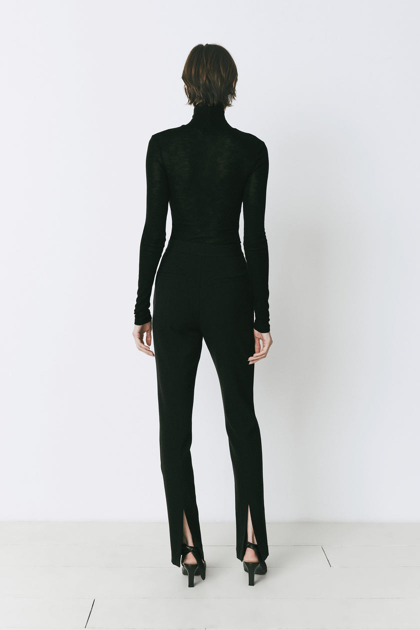 Baïa Slit Hem Pant in black, featuring slit hem and polyester-rayon blend. Paired with a black turtleneck for a chic look