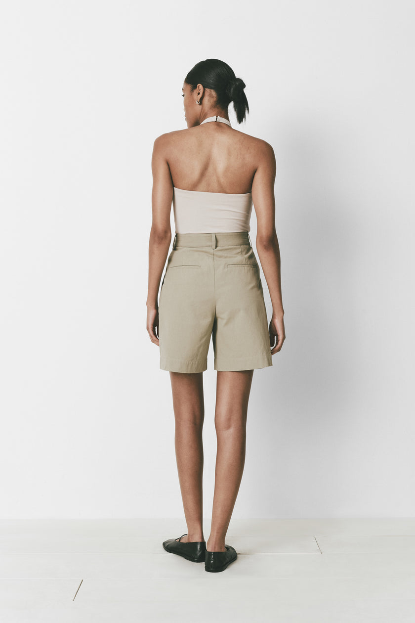 Khaki Alain shorts on a woman, featuring pleat front, belt loops, and mid-thigh length
