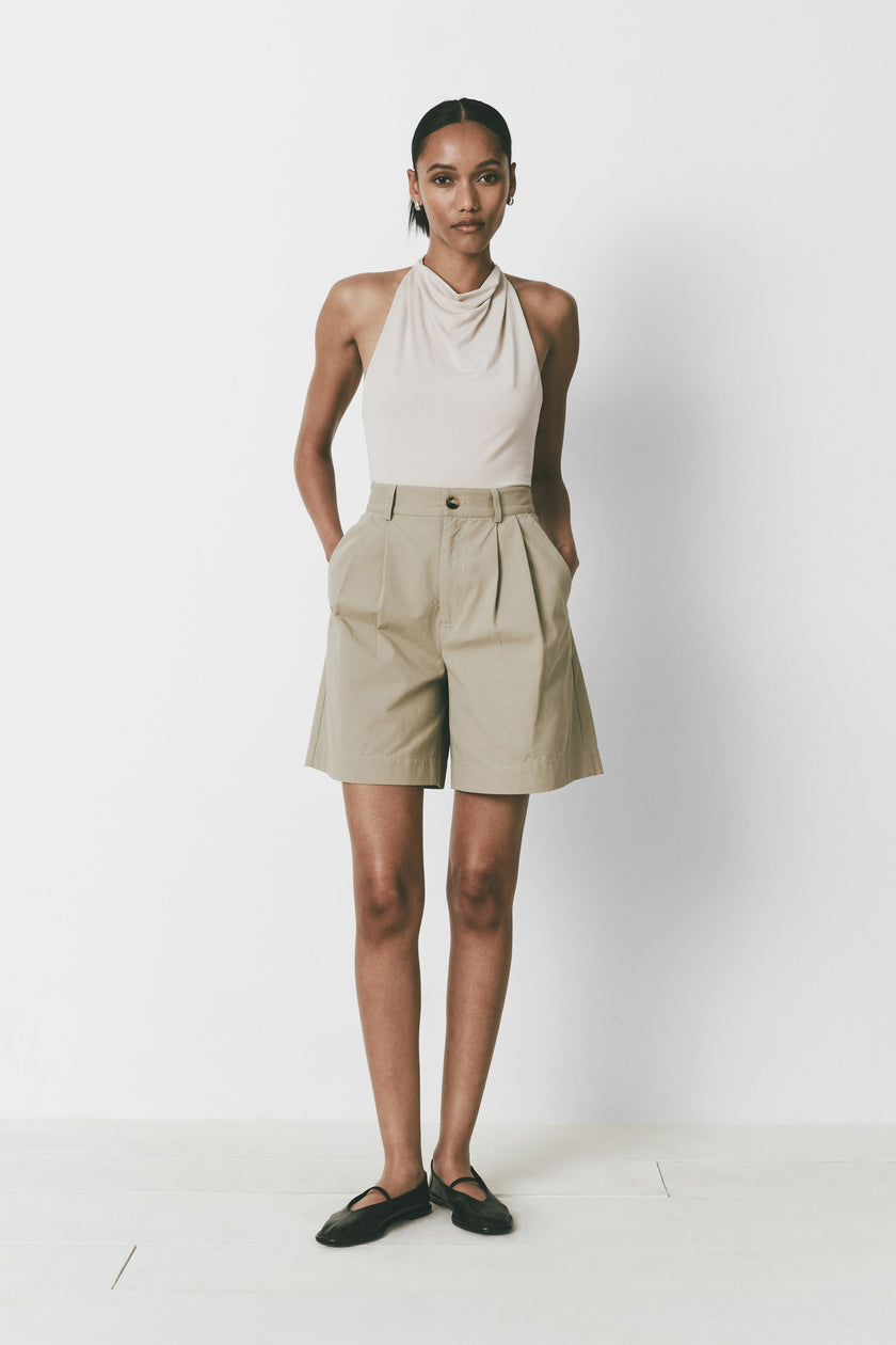 Khaki Alain Shorts with pleat front, button closure and belt loops. Modern woman's outfit with halter top.