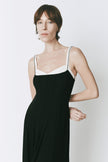 Woman wearing Rue Sophie black midi dress with contrast neckline and delicate straps, styled with black boots.