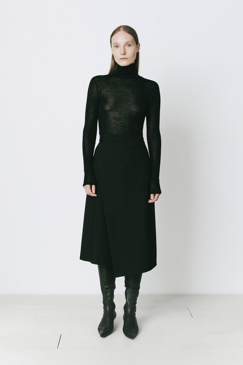 Black Belmont Wrap Skirt with black turtleneck and boots. Versatile, elegant daytime or evening wear.
