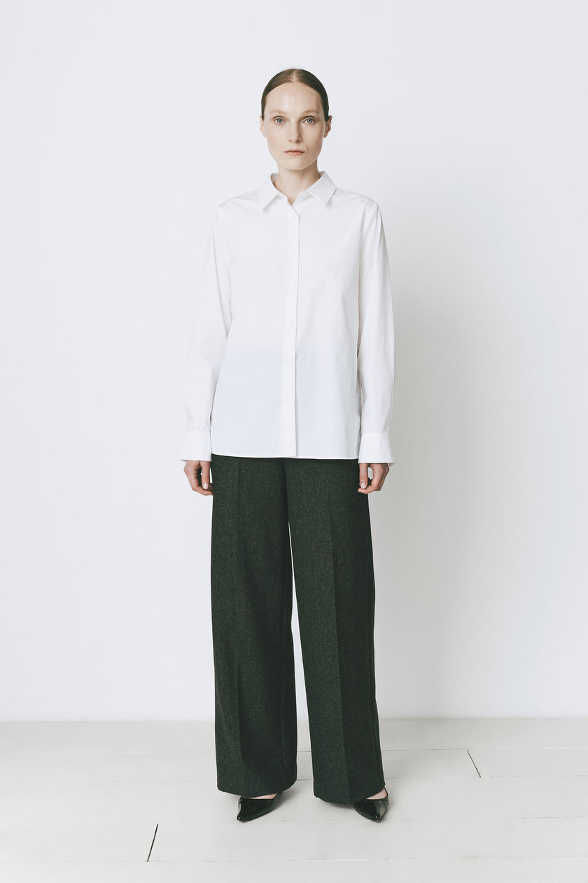 Woman in white cotton Charlot button-down shirt and green trousers, tailored fit
