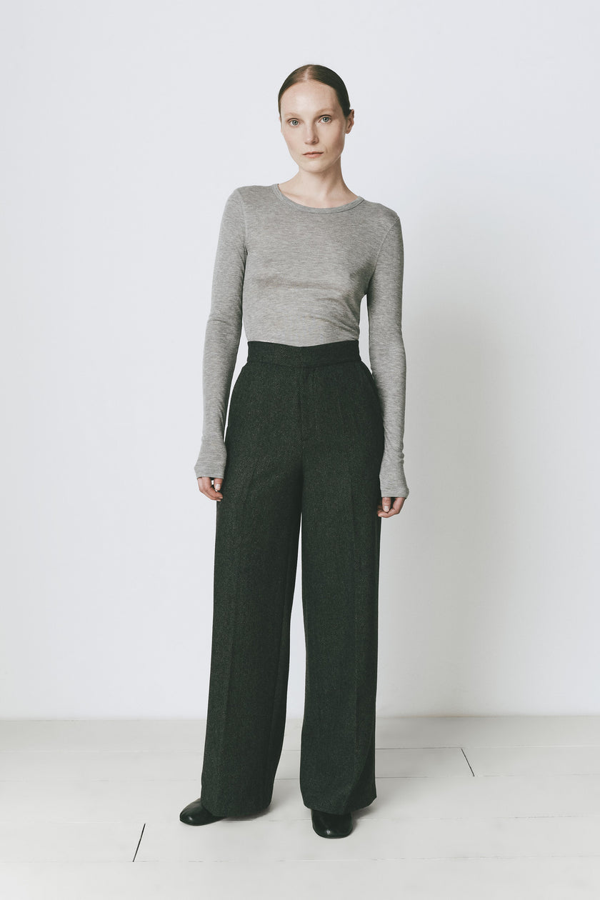 Grey crewneck top and dark green tailored trousers. Modern layering with a streamlined silhouette.