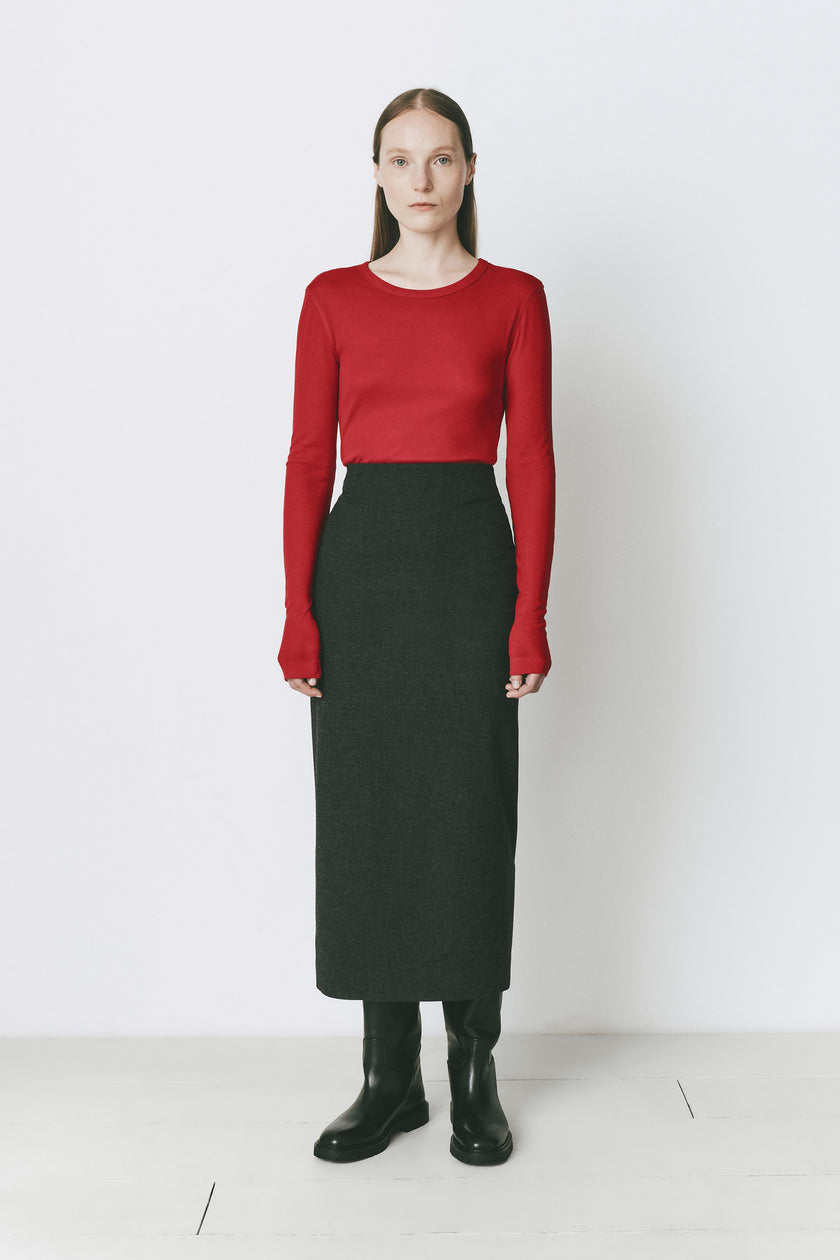 Rouge Clef Long Sleeve Crewneck Top with dark green skirt. Model wears black boots.