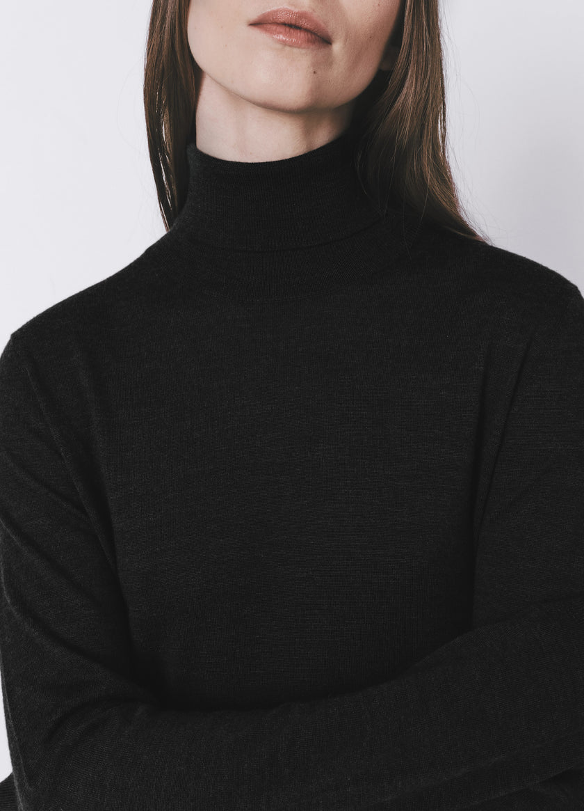 Black wool-silk blend turtleneck sweater on a woman, featuring a high collar and tailored drape, from Rue Sophie