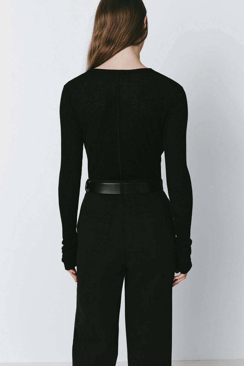 Woman in black outfit, featuring wide leg pant and long sleeve top, creating a sophisticated and versatile look