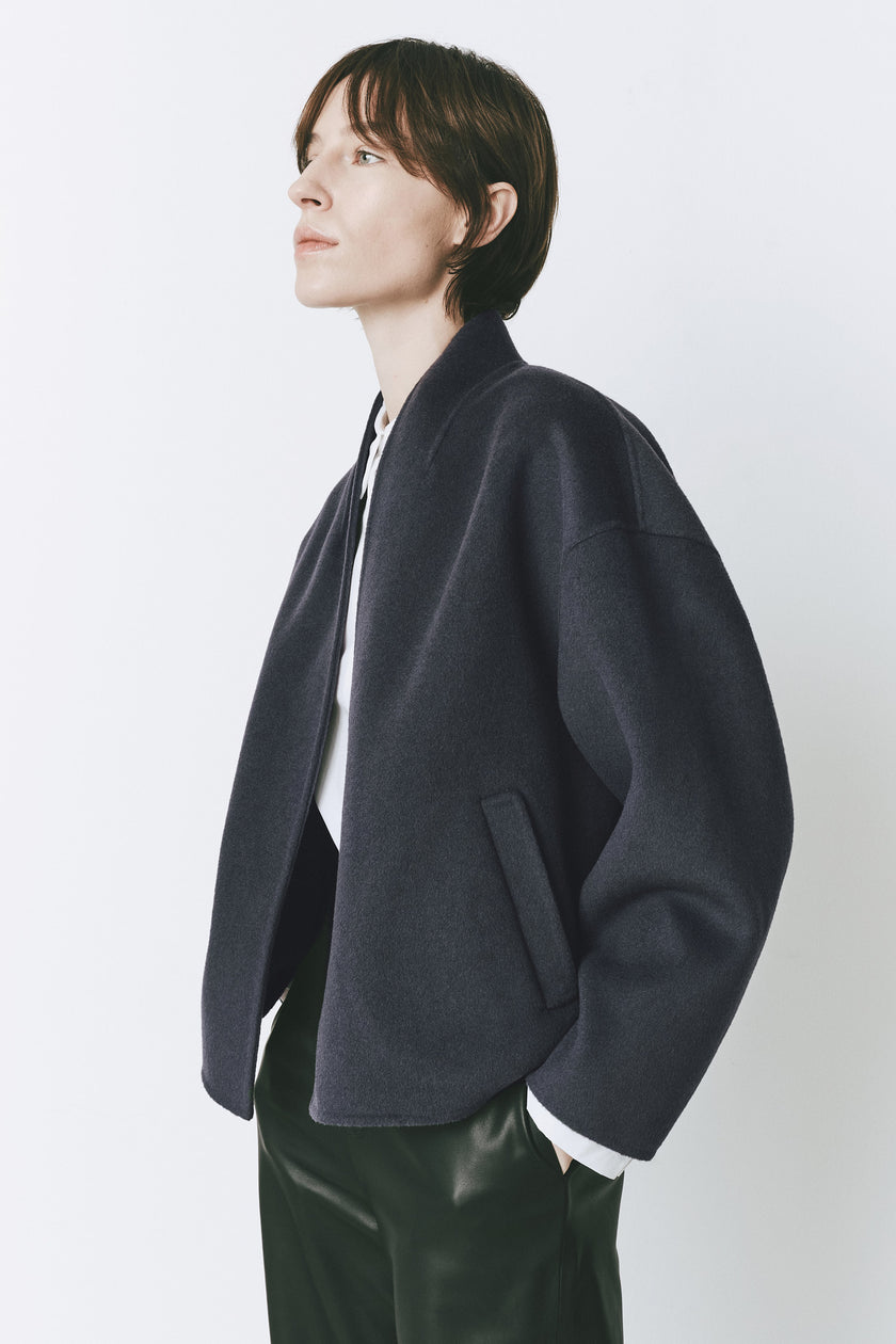 Topaz blue wool-cashmere Jaurès Shawl Collar Jacket, open-front, woman wearing with green leather pants.