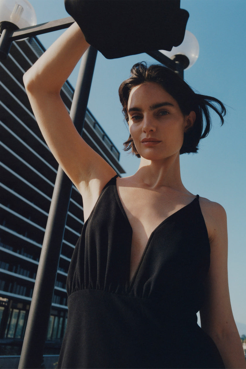 Liana Notch V-Neck Dress in black, model wearing the V-neck dress outdoors.