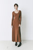 Model wearing the Mignet Sweater Dress, a long, oversized brown knit dress with a round neck and long sleeves