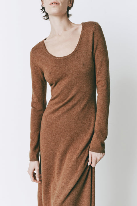 Model wearing the Mignet Sweater Dress, a long, oversized brown knit dress with a round neck and long sleeves