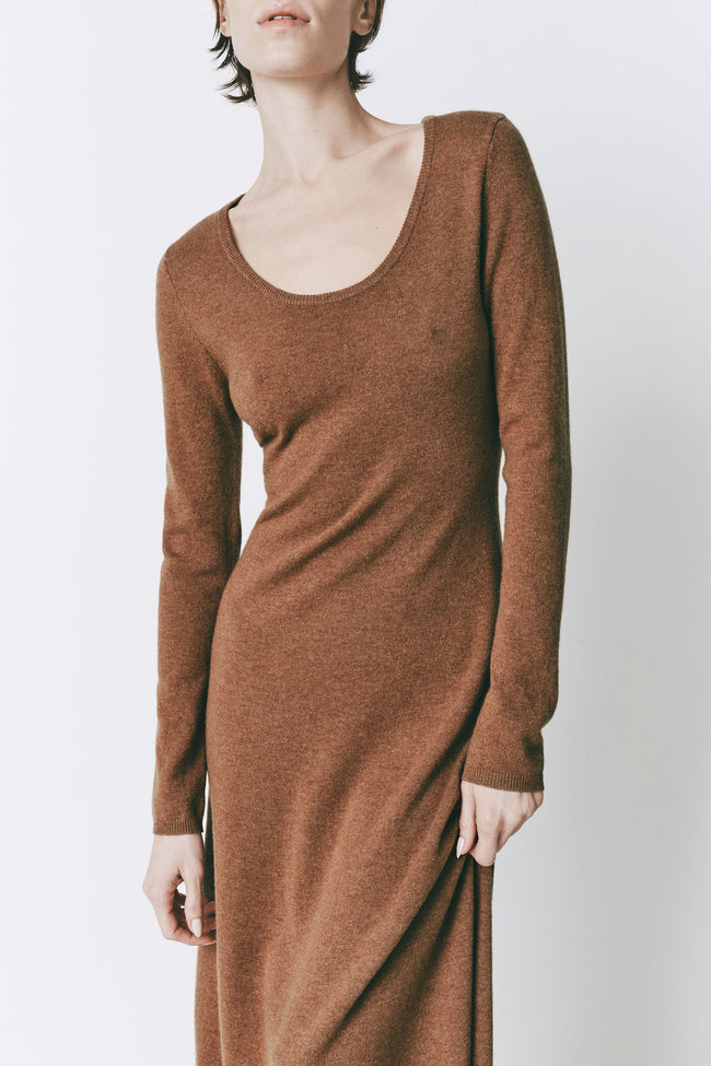 Model wearing the Mignet Sweater Dress, a long, oversized brown knit dress with a round neck and long sleeves