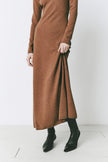 Model wearing the Mignet Sweater Dress, a long, oversized brown knit dress with a round neck and long sleeves