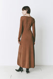 Model wearing the Mignet Sweater Dress, a long, oversized brown knit dress with a round neck and long sleeves