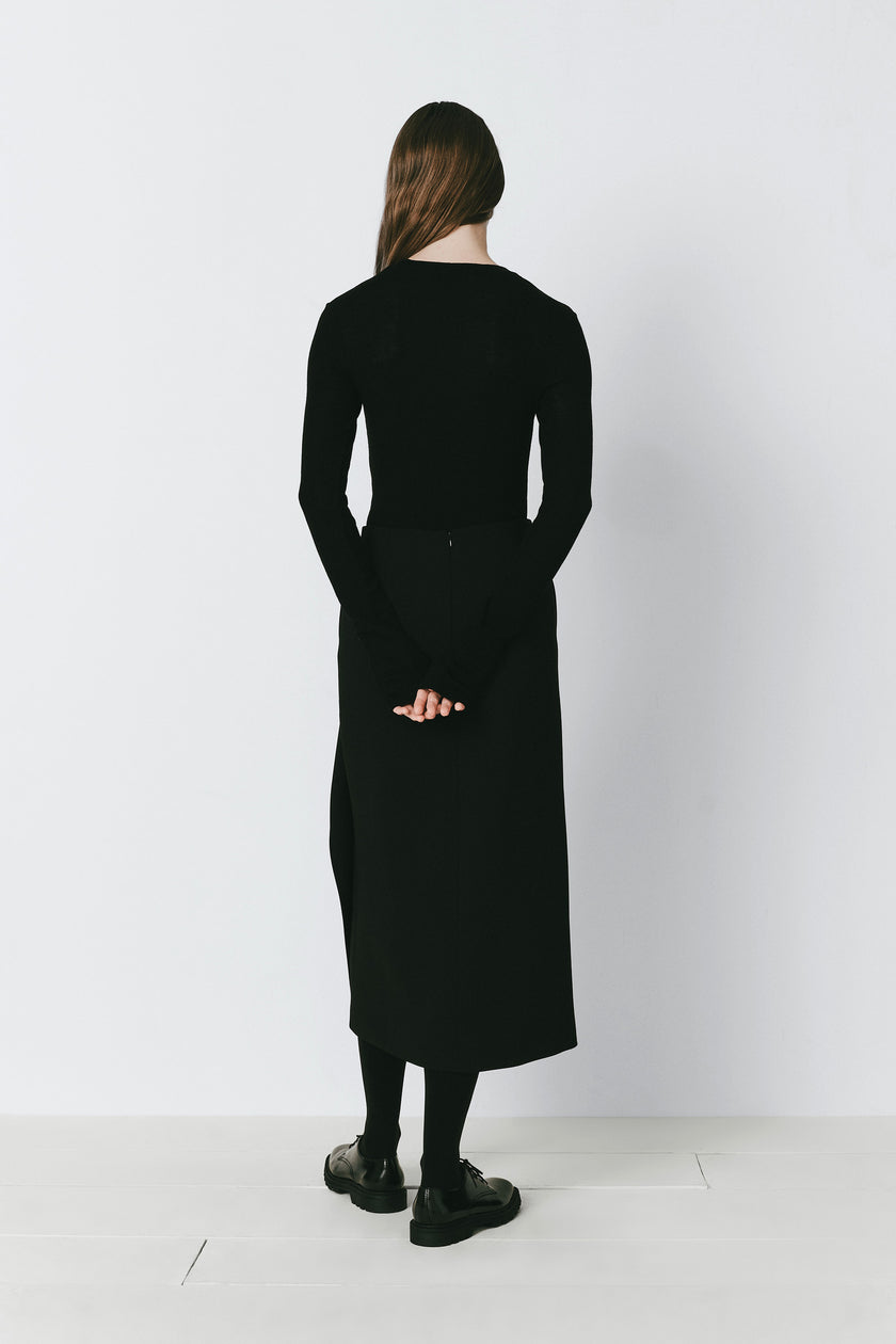 Black Oudine Sheer Wool Top and skirt. Woman in a black top, midi skirt, and shoes, back view.