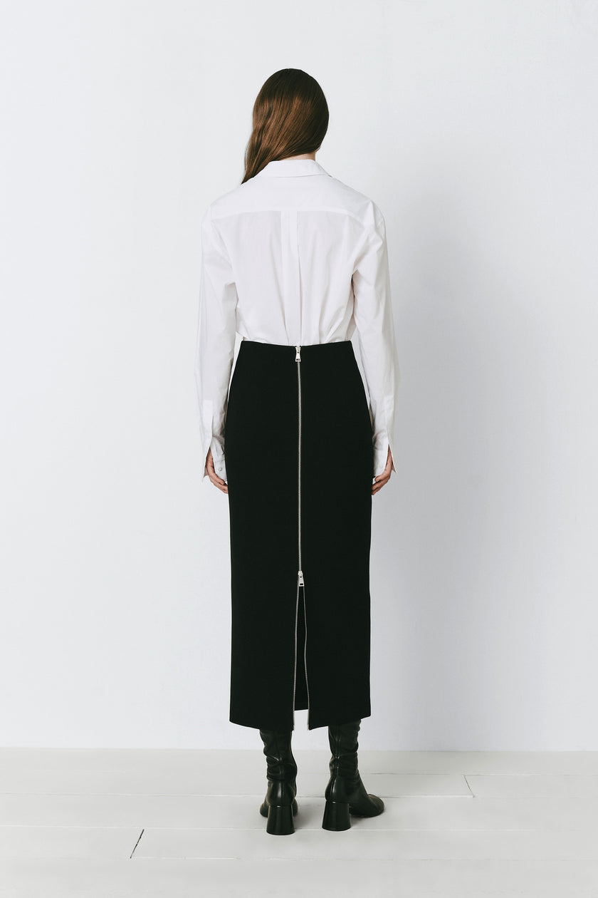Black Raoulet back zip-up pencil skirt, white shirt, and boots, modern professional look
