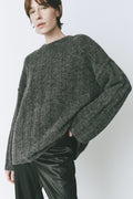 Model wearing an oversized sweater with a round neck, dropped shoulders, and wide sleeves, in soft luxury knitwear