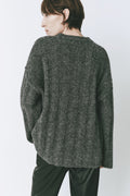 Model wearing an oversized sweater with a round neck, dropped shoulders, and wide sleeves, in soft luxury knitwear